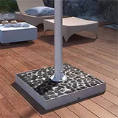 Black river stones base mount for outdoor TV with stainless steel pole on a wooden floor in Qatar.