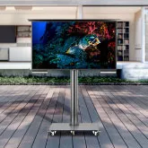 Outdoor TV in wheel-based floor mount in a patio with a white furnished house in the background in Bahrain.